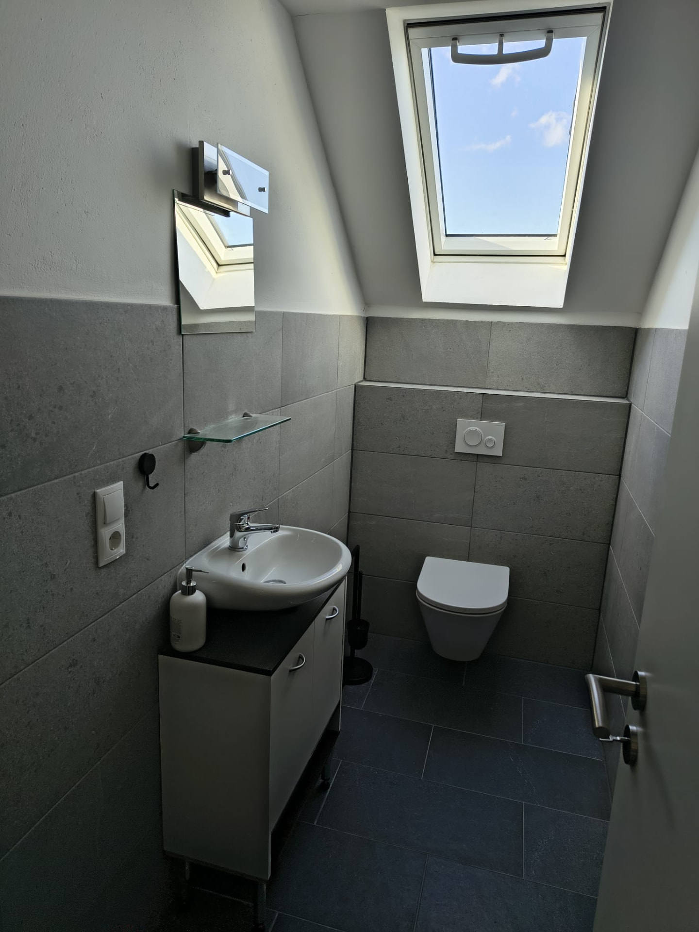 Gäste-WC mit Dachfenster und grauer Steinoptik